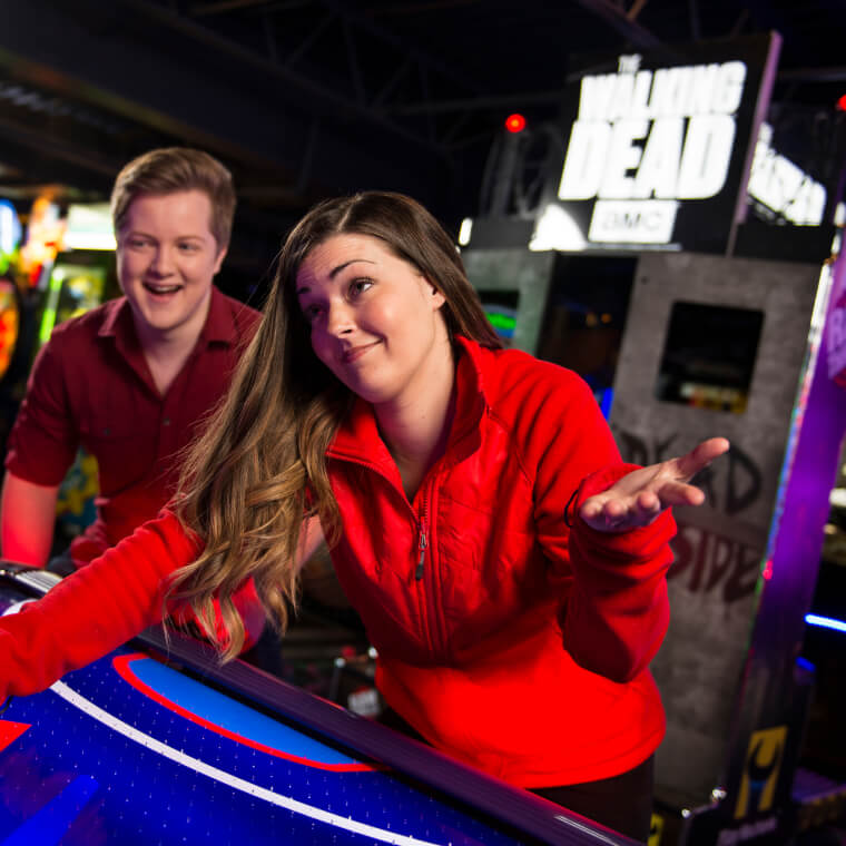 Three adults playing airhockey