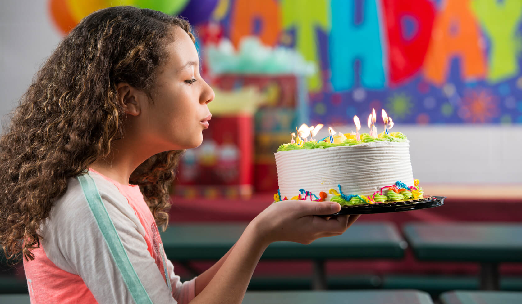 Young girl blowing out candles on a birthday cake