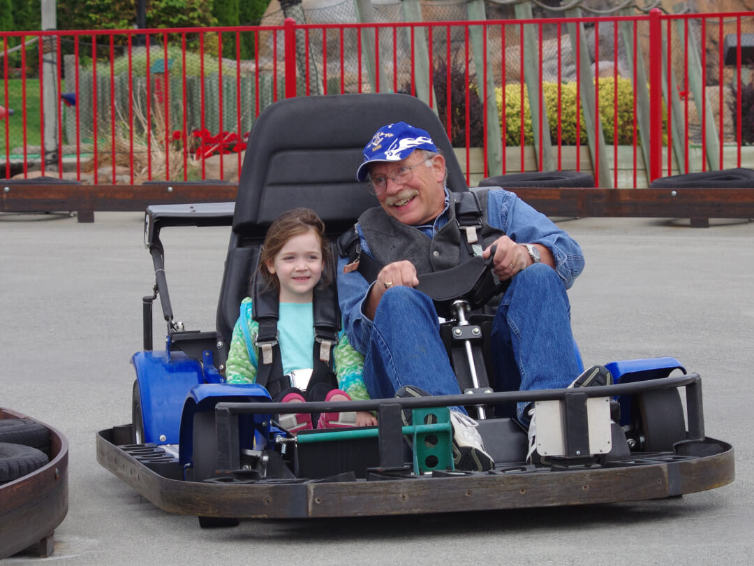 Grandpa and granddaughter driving on the go kart track