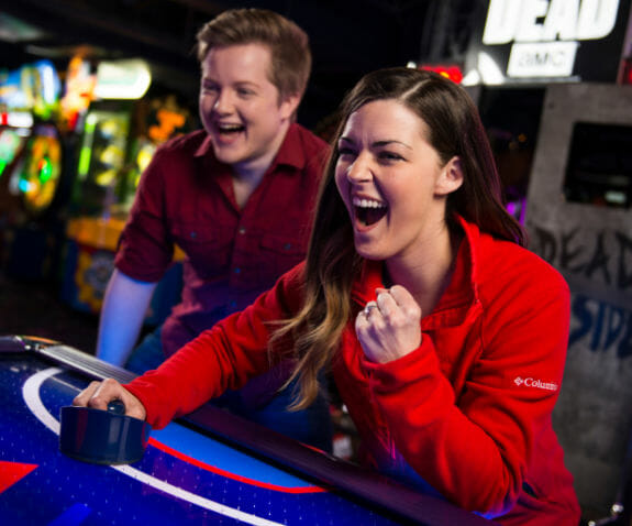 Young woman excitedly playing air hockey