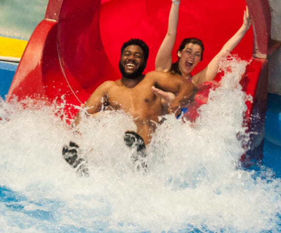 Two adults coming down a water slide