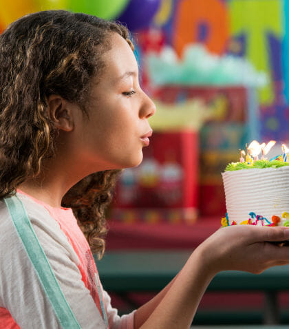 Young girl blowing out candles on a birthday cake