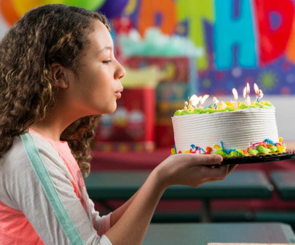 Young girl blowing out candles on a birthday cake