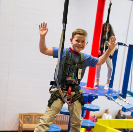 Young boy in a harness on the ropes course