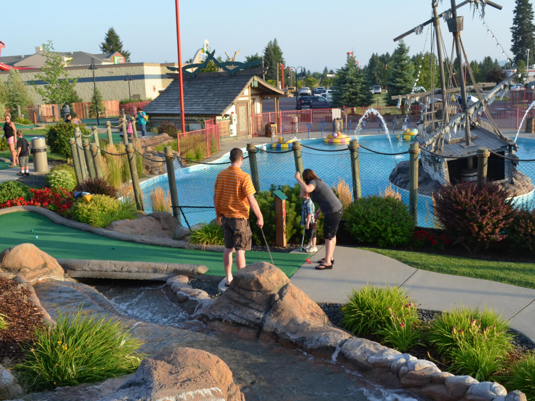 Family playing outdoor mini golf