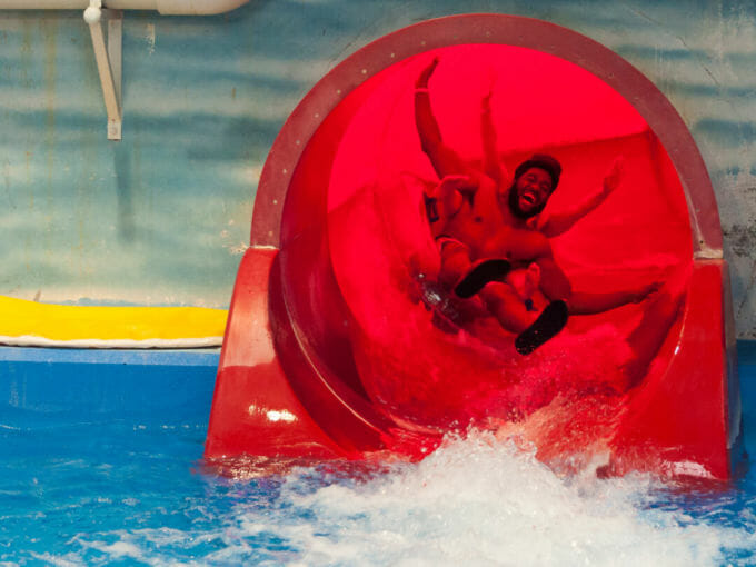 Adults joyfully screaming coming out of a waterslide