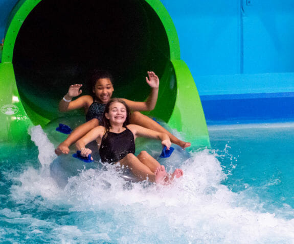 Two young girls riding down the Constrictor on a double tube