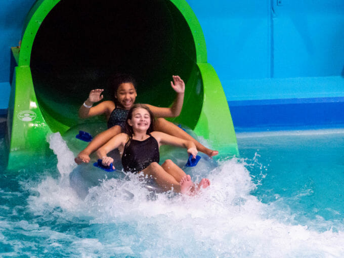 Two young girls riding down the Constrictor on a double tube