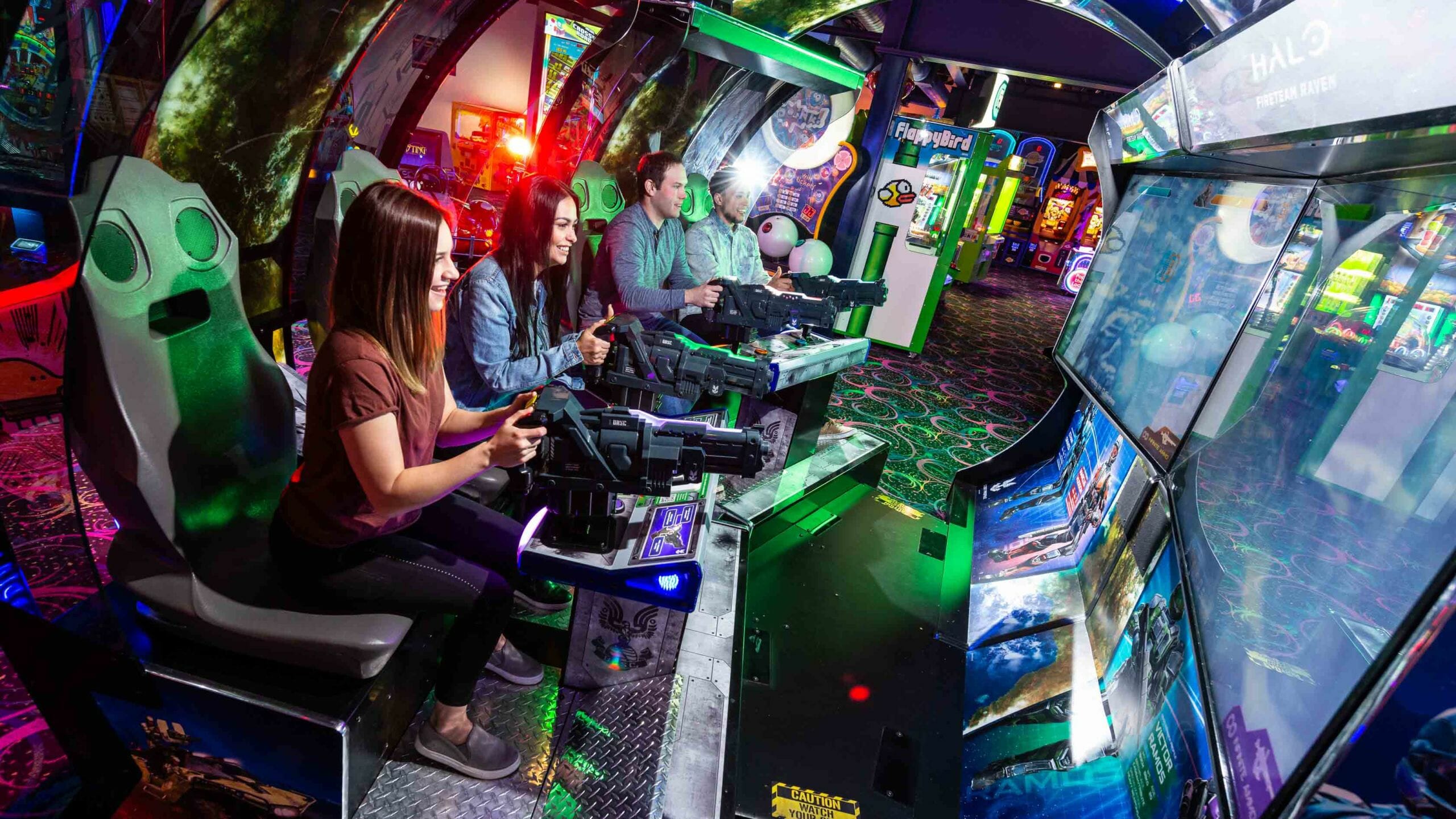 Group of adult friends playing an arcade shooting game