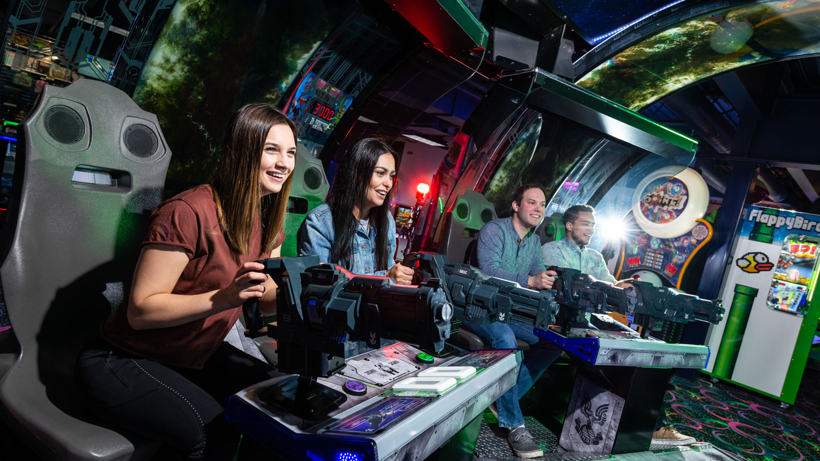 Group of adult friends playing an arcade shooting game