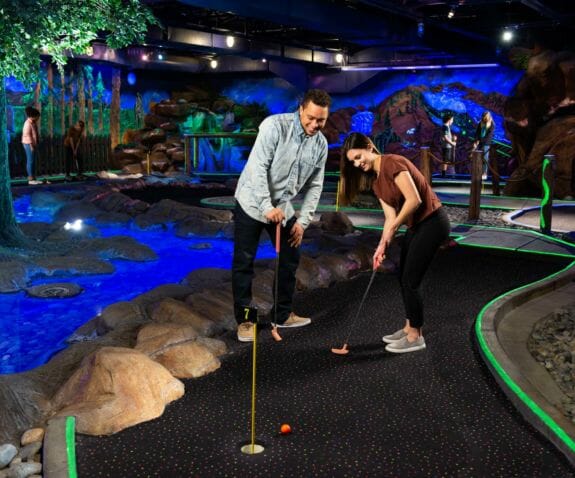 Young couple playing indoor mini golf