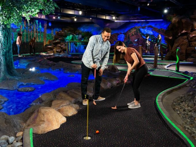 Young couple playing indoor mini golf