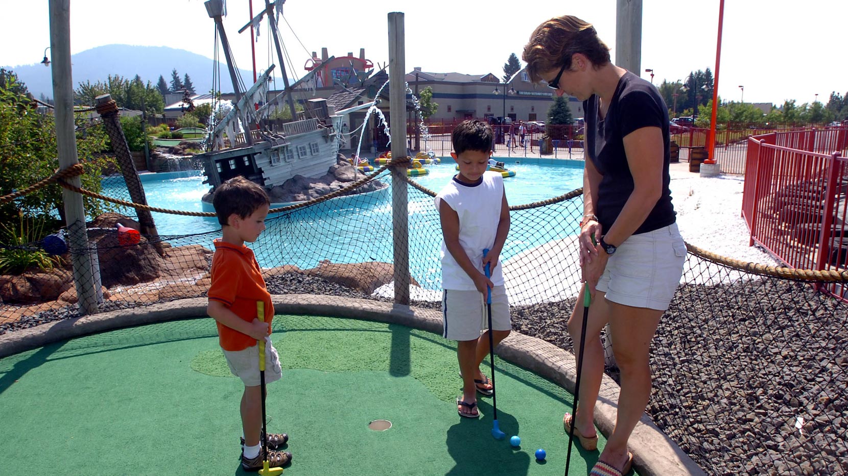 Mom and two sons playing outdoor mini golf
