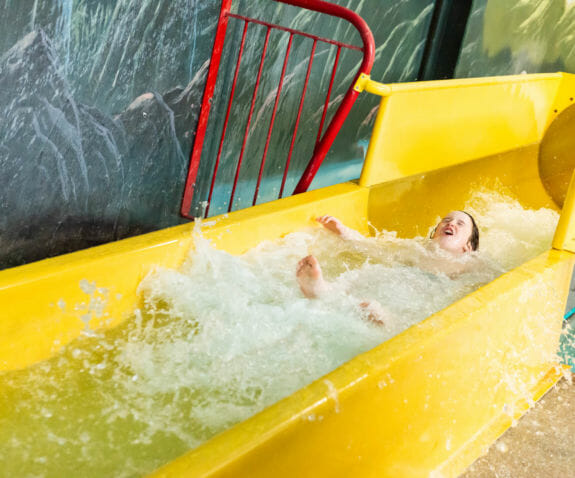 Young boy sliding down the water slide