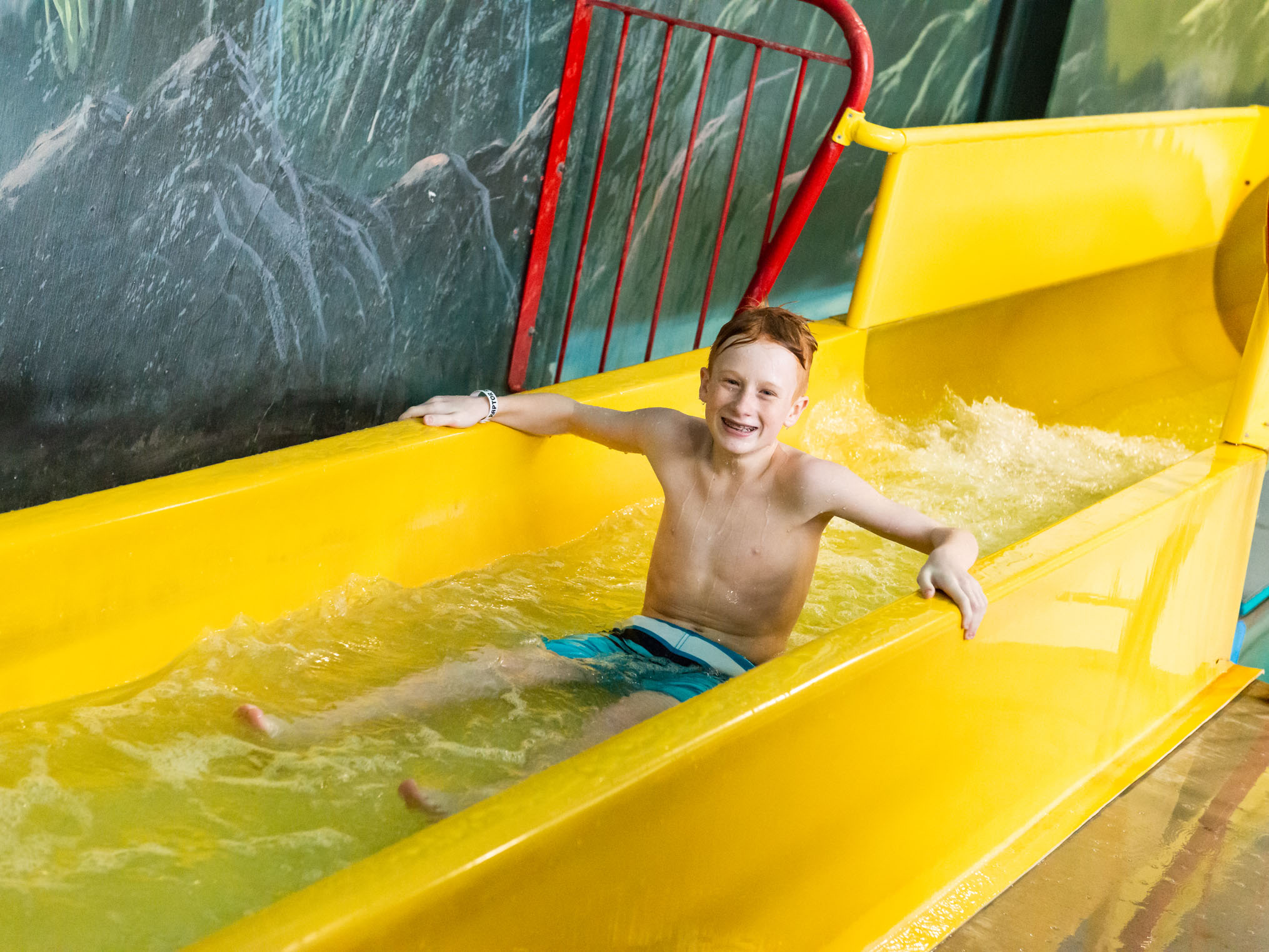 Young boy sitting up at the end of the slide