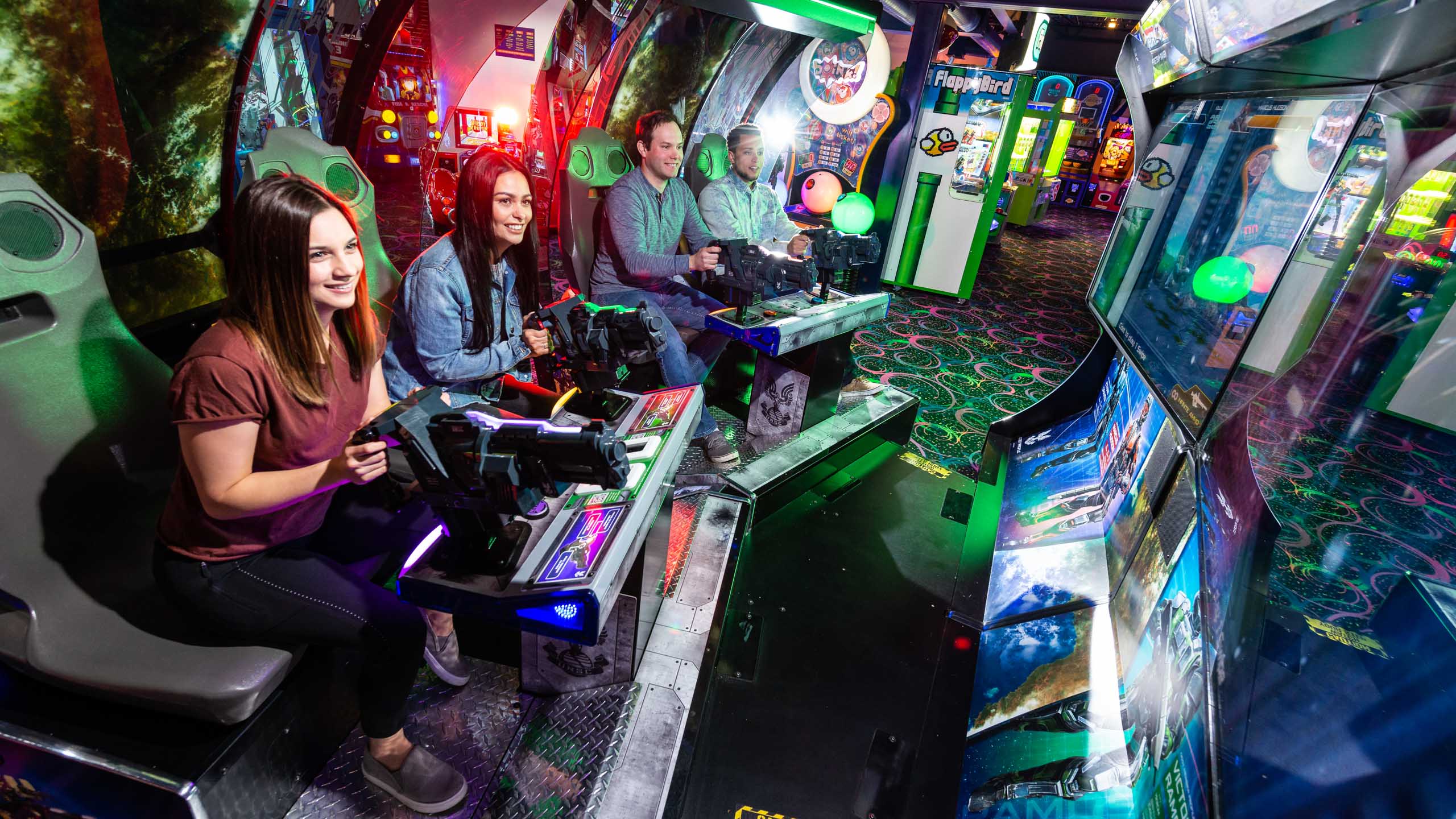 Group of young adults playing a group shooting game in the arcade